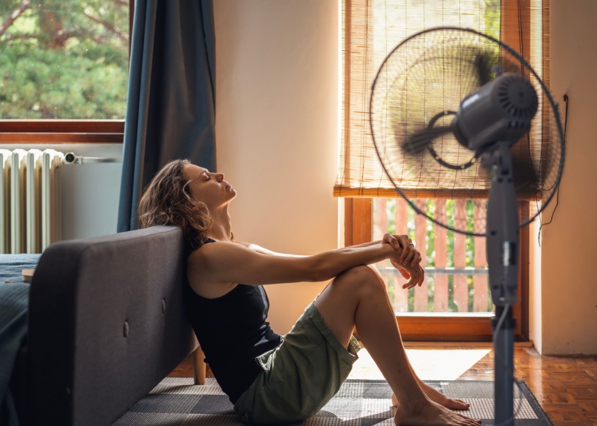 Woman sitting in front of her fan on a hot day when her AC is broken