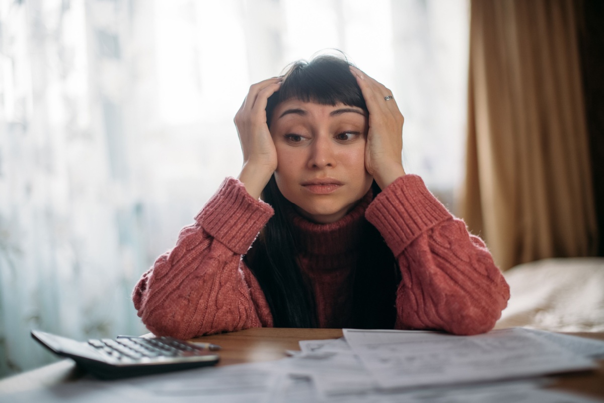 exasperated woman with her head in her hands as she calculates rising heating bills