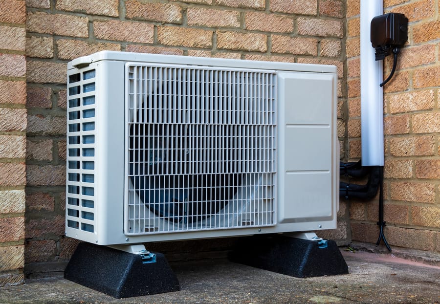 Heat pump maintenance in front of brick wall