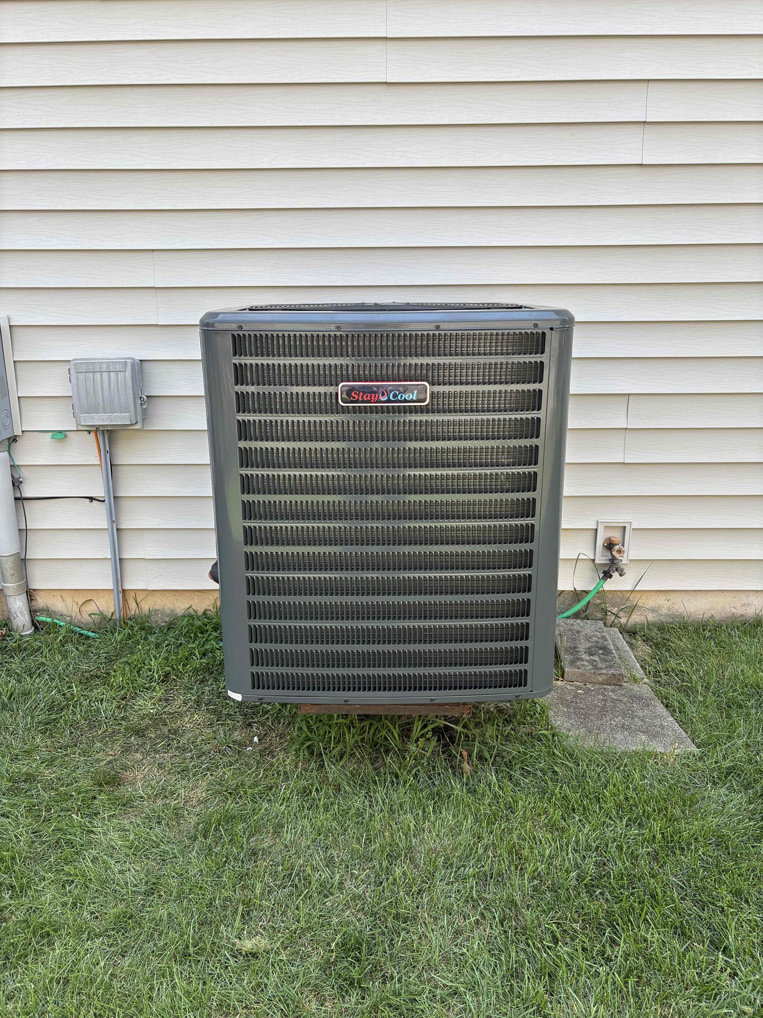 Outdoor air conditioning unit on grass on the side of a house